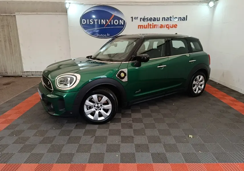 Vue de profil droit d'une MINI Countryman hybride rechargeable vert foncé avec toit noir en intérieur showroom.