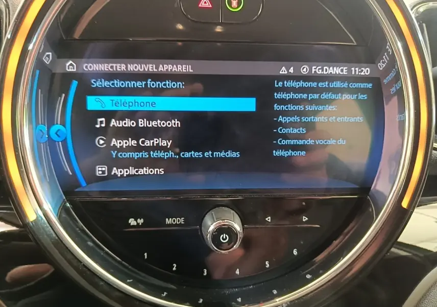 Gros plan sur l'écran tactile circulaire du tableau de bord du MINI Countryman gris clair affichant les options Apple CarPlay et Bluetooth.