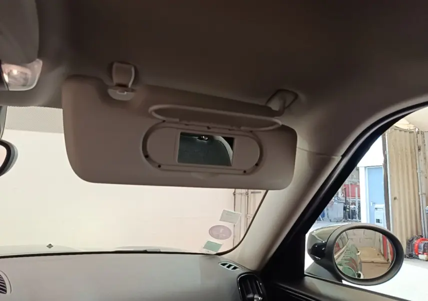 Intérieur du MINI Countryman Cooper SE 2021, vue côté passager avec pare-soleil beige et rétroviseur extérieur noir.