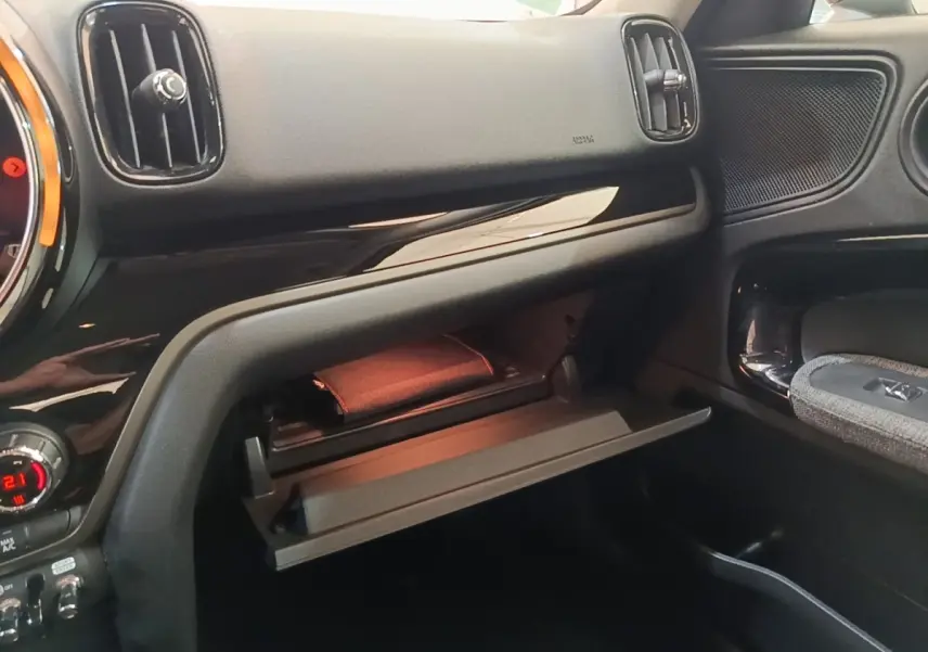 Intérieur MINI Countryman Cooper SE 2021, vue côté passager sur boîte à gants ouverte et tableau de bord noir.