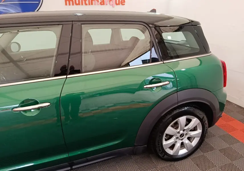 Vue latérale droite d'une MINI Countryman hybride rechargeable vert foncé avec toit blanc et jantes argentées.