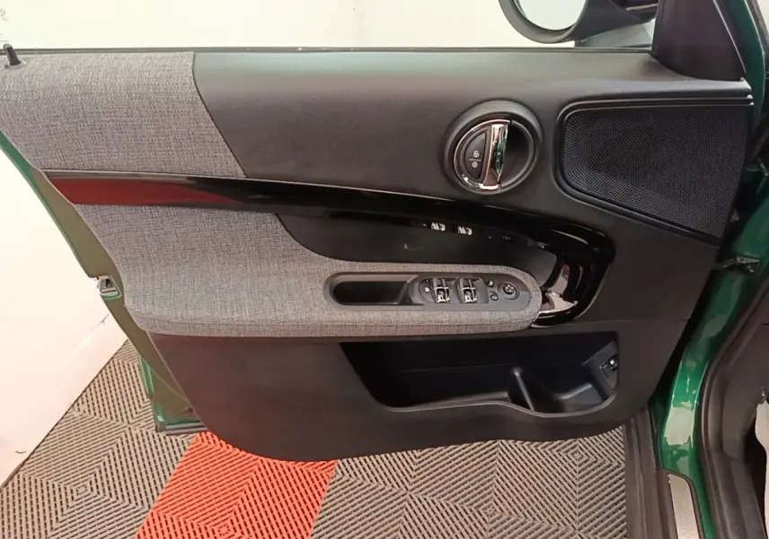 Vue intérieure côté gauche de la porte avant d’un MINI Countryman gris clair avec garniture tissu et commandes électriques.