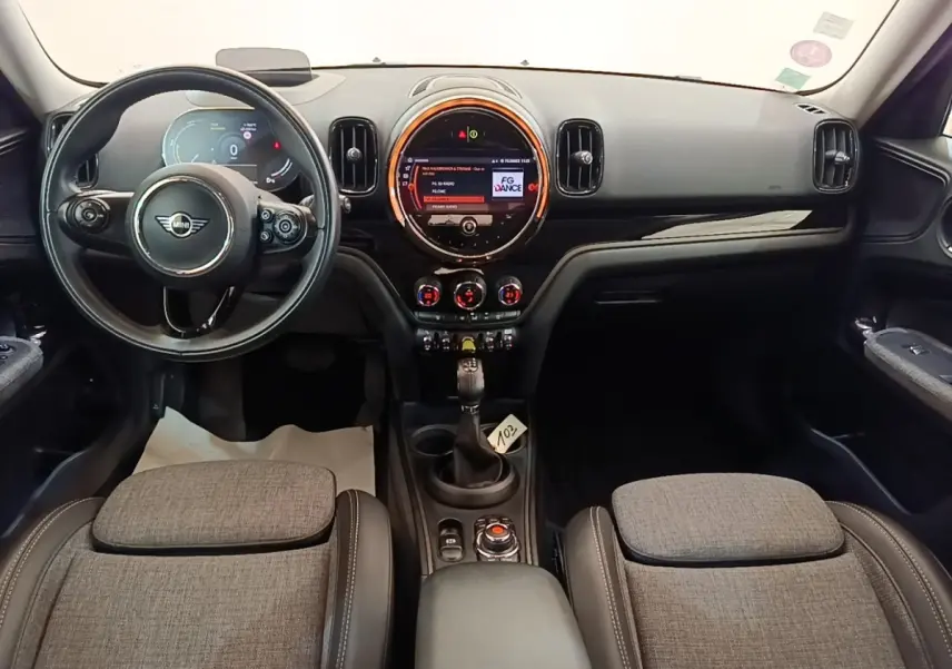 Intérieur avant du MINI Countryman Cooper SE gris clair, tableau de bord moderne avec écran central rond et volant multifonctions.