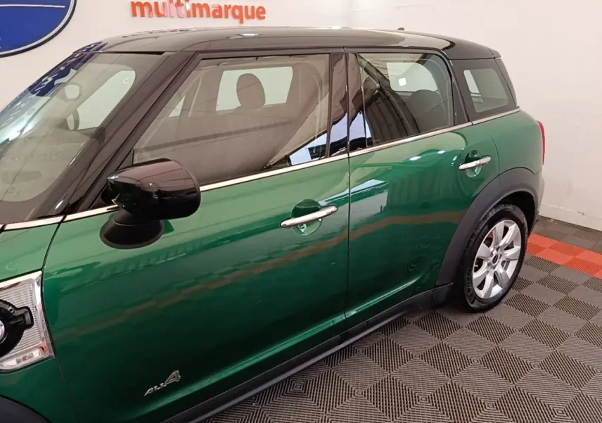 Vue latérale droite d'une MINI Countryman hybride rechargeable verte avec toit noir et jantes argentées.
