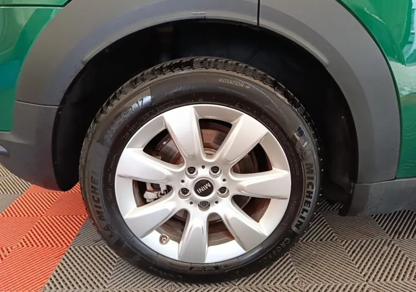 Gros plan sur la roue avant gauche avec jante argentée et pneu Michelin d’un MINI Countryman vert.