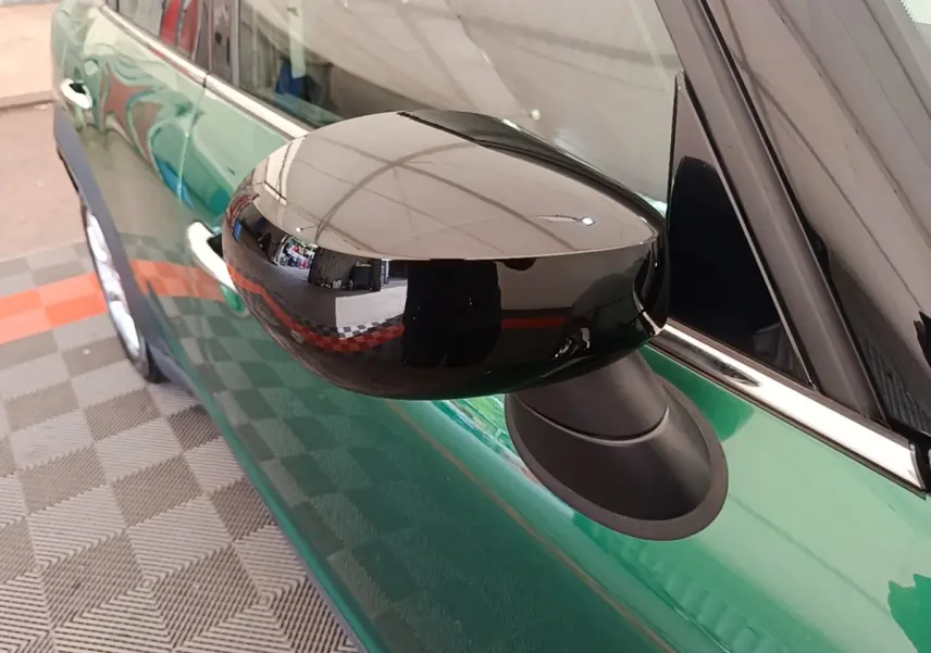 Gros plan sur le rétroviseur noir brillant côté gauche d'une MINI Countryman vert foncé, avec reflet net.