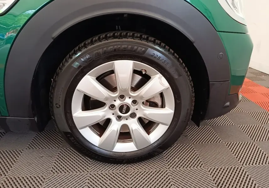 Gros plan sur la roue avant droite argentée d’un MINI Countryman vert avec logo MINI au centre de la jante.