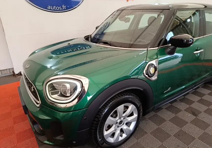 Vue 3/4 avant droit d'une MINI Countryman Cooper SE hybride rechargeable vert foncé avec toit noir et jantes argentées.