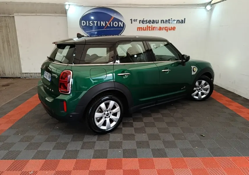 Vue 3/4 arrière droite d'un MINI Countryman hybride rechargeable vert foncé avec toit noir dans un showroom.