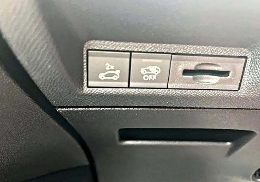 Détail intérieur montrant les boutons d'ouverture du coffre et de désactivation d'assistance sur Peugeot 3008 gris Artense.