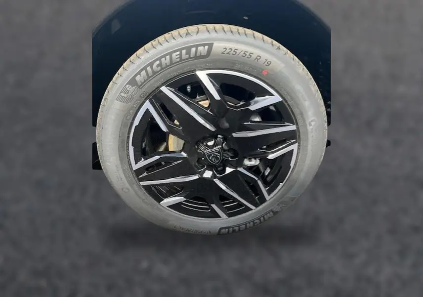 Gros plan sur la jante alu noire et argentée avec logo Peugeot, montée d’un pneu Michelin 225/55 R19.