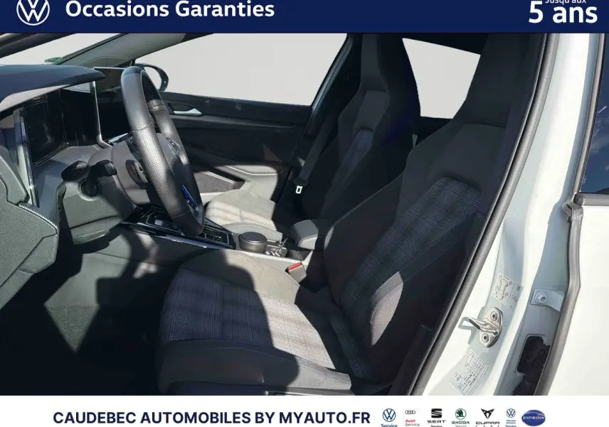 Vue intérieure côté conducteur de la Volkswagen Golf 1.5 eHybrid blanche, sièges sport en tissu à motifs.