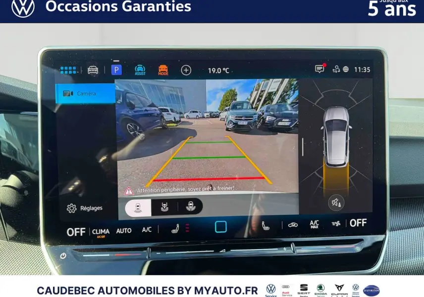 Écran tactile intérieur affichant la caméra de recul et la vue à 360° d'une Volkswagen Golf blanche en stationnement.