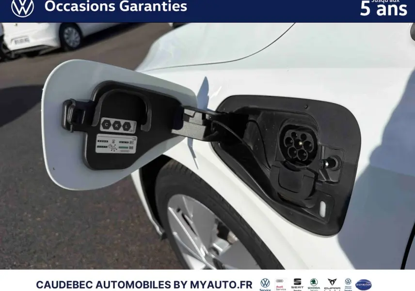 Prise de recharge ouverte côté gauche d’une Volkswagen Golf 1.5 eHybrid blanche, jante visible en arrière-plan.