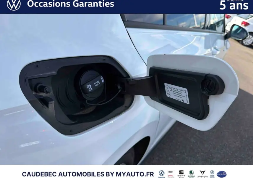 Gros plan sur la trappe de recharge ouverte côté gauche d’une Volkswagen Golf 1.5 eHybrid blanche, avec bouchon visible.