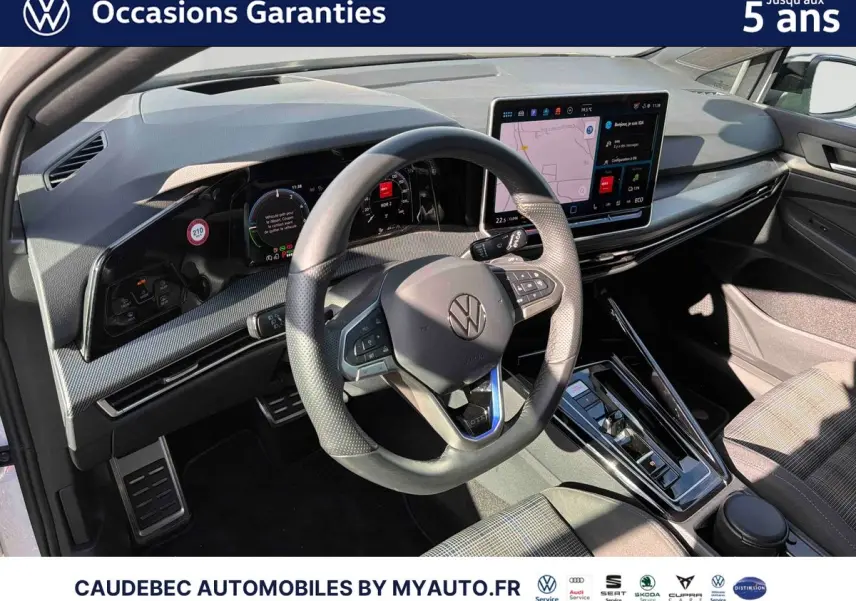 Vue intérieure du poste de conduite de la Volkswagen Golf 1.5 eHybrid 2025, volant cuir multifonction et grand écran tactile central.