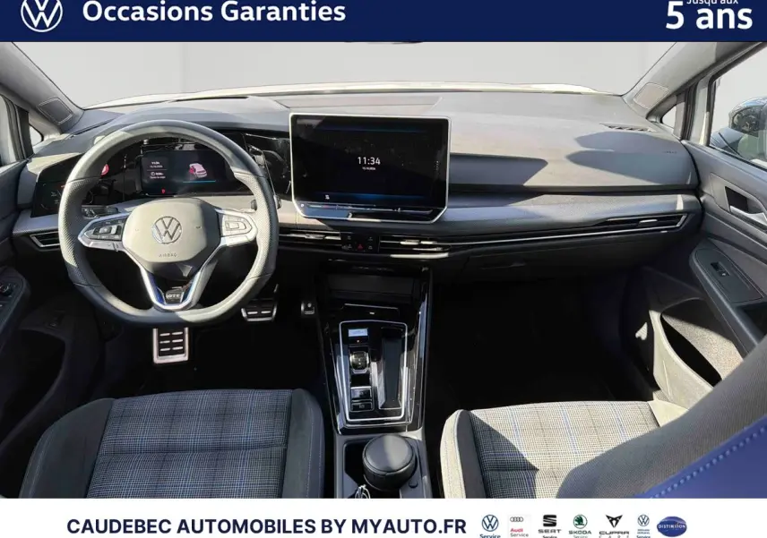 Vue intérieure avant de la Volkswagen Golf 1.5 eHybrid blanche, avec volant multifonction et écran tactile central.