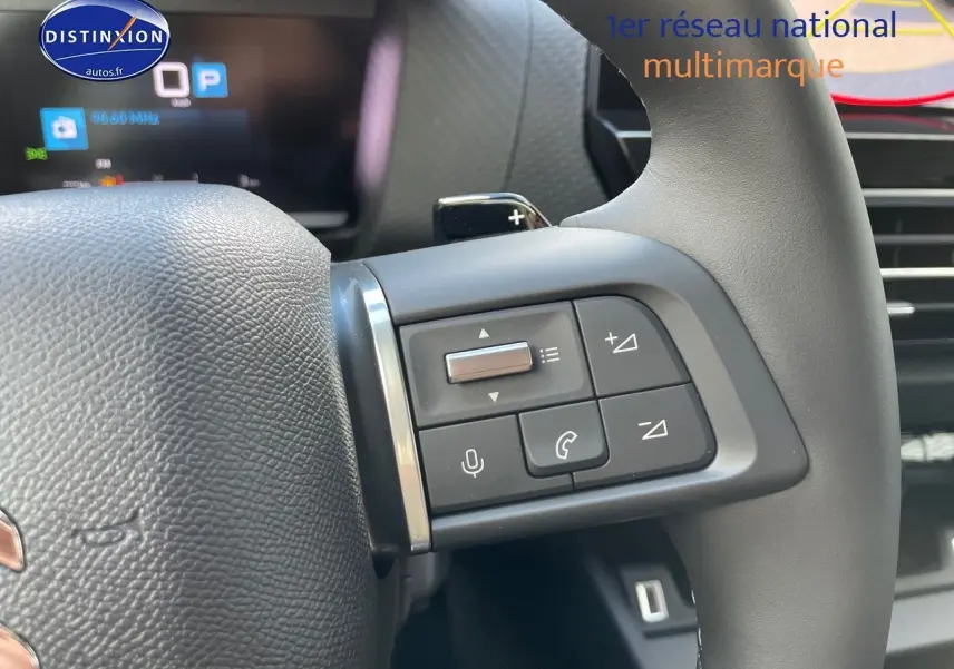 Gros plan sur les commandes au volant à droite du Citroën C4 2024, finition gris platinium métal, avec boutons multifonctions.