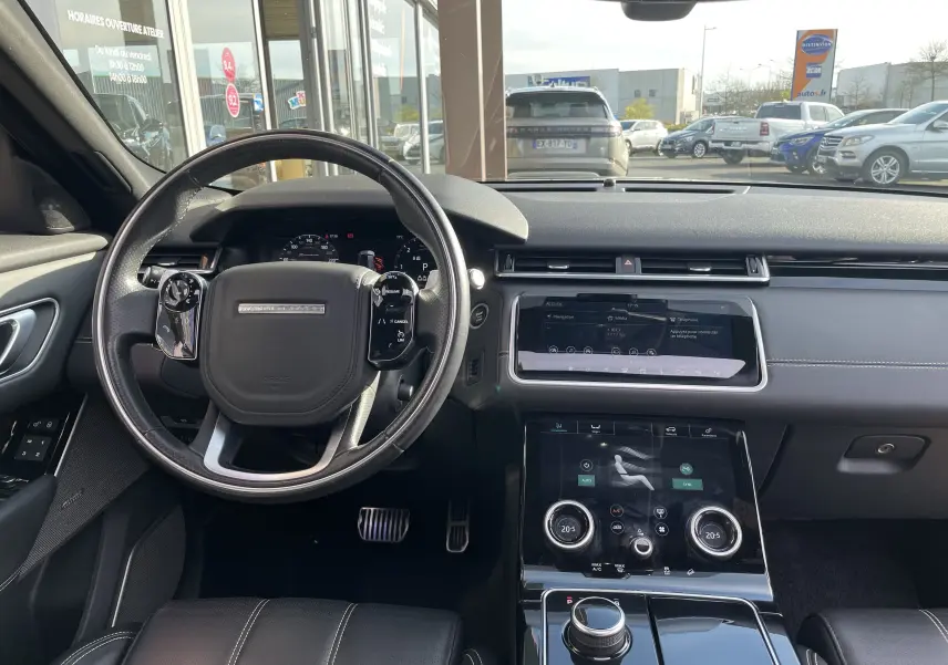Vue intérieure du tableau de bord et volant du Range Rover Velar noir Santorini, avec écran tactile et finitions cuir noires.