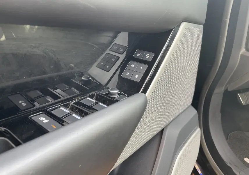 Gros plan sur la porte côté conducteur du Range Rover Velar noir Santorini, mettant en valeur les commandes de vitres et le haut-parleur Meridian.