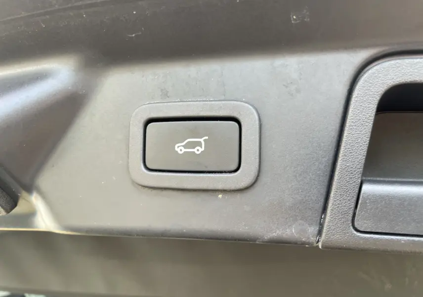 Gros plan sur le bouton d'ouverture électrique du coffre dans l'habitacle du Range Rover Velar noir Santorini 2019.