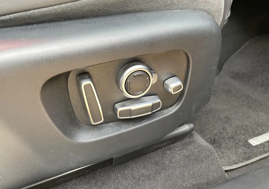 Gros plan sur les commandes électriques de réglage du siège côté conducteur du Range Rover Velar noir Santorini 2019.