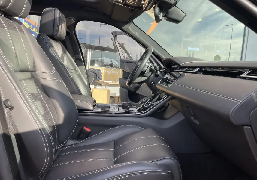 Intérieur cuir noir du Range Rover Velar 2019 vu côté conducteur, avec tableau de bord moderne et toit panoramique.