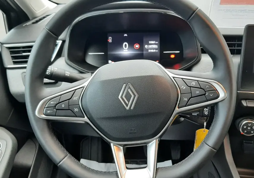 Vue rapprochée du volant noir de la Renault Clio V E-Tech Full Hybrid 145 Evolution avec tableau de bord numérique allumé.