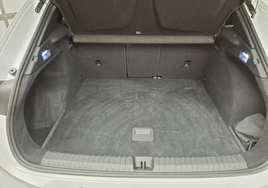 Coffre ouvert d'une CUPRA TERRAMAR blanc Nevada, vue de l'arrière montrant l'espace de chargement vide et l'éclairage intérieur.