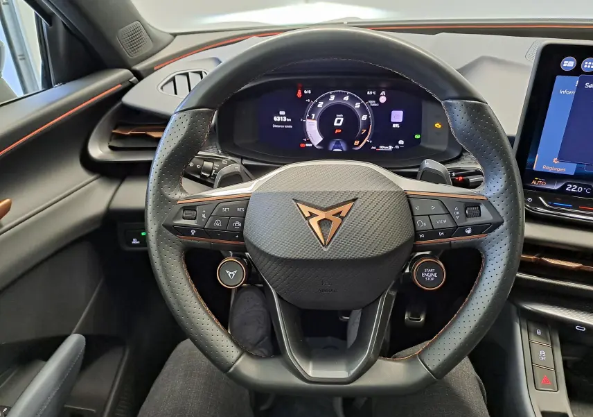 Vue intérieure centrée sur le volant perforé noir avec logo CUPRA cuivré et tableau de bord numérique du Terramar 2025.