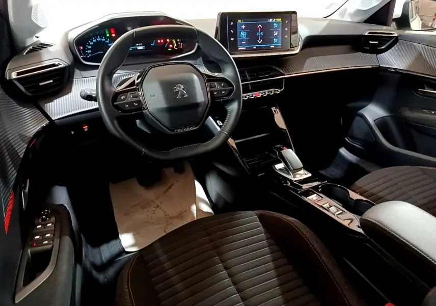 Vue intérieure avant de la Peugeot 208 électrique Active Business, tableau de bord avec écran tactile central et volant cuir multifonctions.