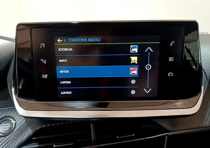 Écran tactile central affichant les stations radio dans l’habitacle d’une Peugeot 208 électrique blanche.