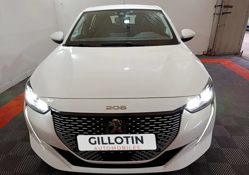 Vue avant d'une Peugeot 208 électrique Active Business blanche avec phares LED allumés et calandre noire distinctive.