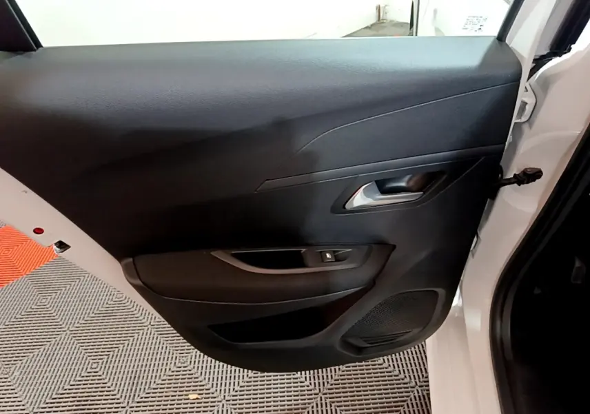Vue intérieure de la porte arrière droite noire d'une Peugeot 208 électrique blanche, avec poignée et commande de vitre.