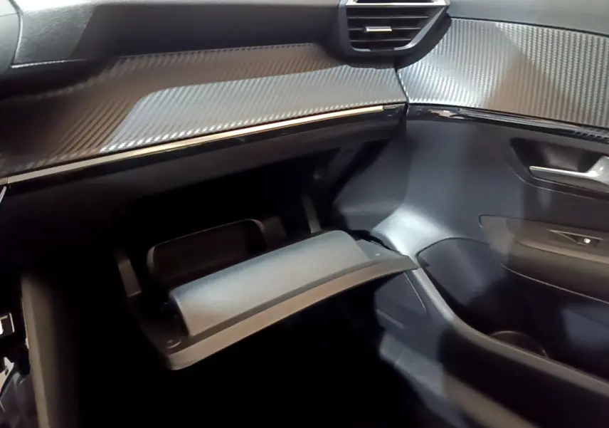 Intérieur côté passager du Peugeot 208 électrique blanc, vue sur la boîte à gants ouverte et le tableau de bord noir.