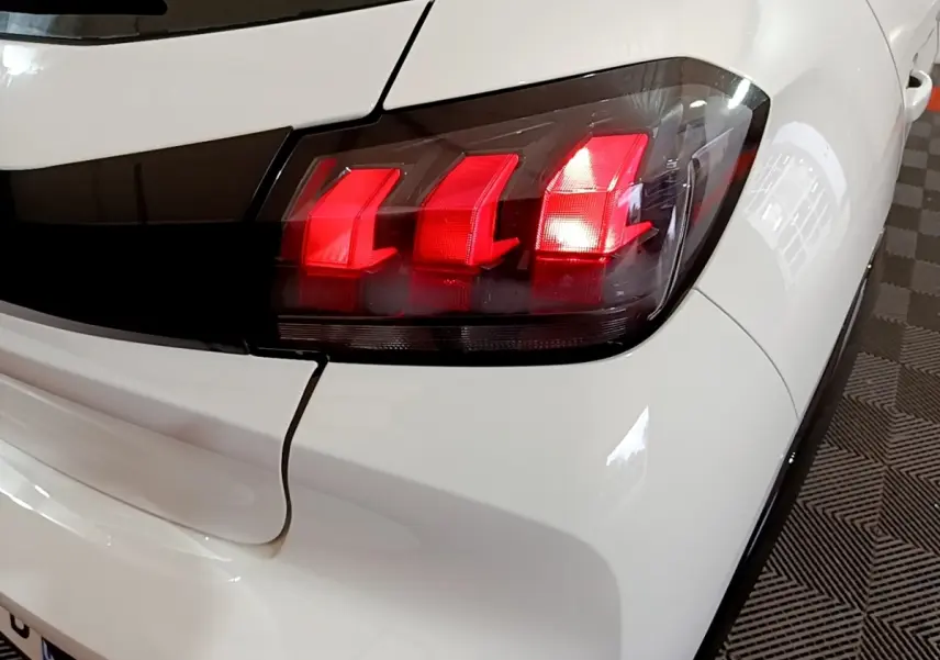 Gros plan sur le feu arrière droit rouge d'une Peugeot 208 électrique Active Business blanche, vue arrière côté droit.