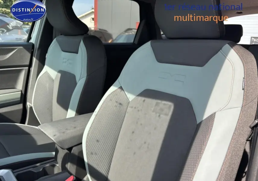 Vue intérieure rapprochée des sièges avant gris clair et foncé du Dacia Bigster avec accoudoir central visible.