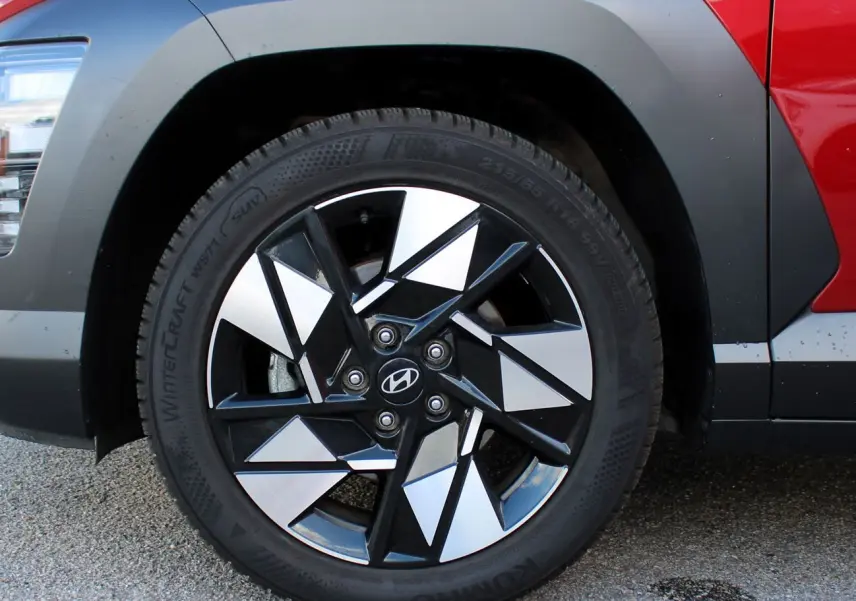 Gros plan sur la roue avant gauche du Hyundai Kona 2024 rouge Ultimate Metal avec jante alliage noire et argent.