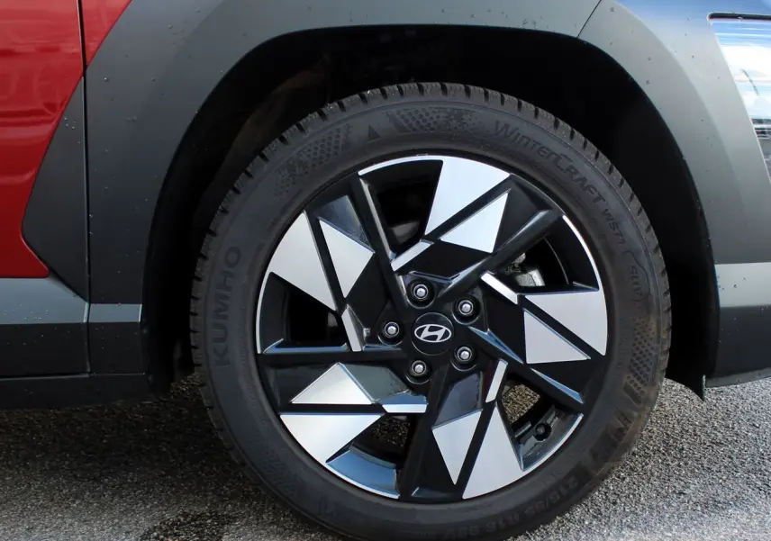 Gros plan sur la roue avant droite du Hyundai Kona 2024 rouge Ultimate avec jante noire et argent à motifs géométriques.