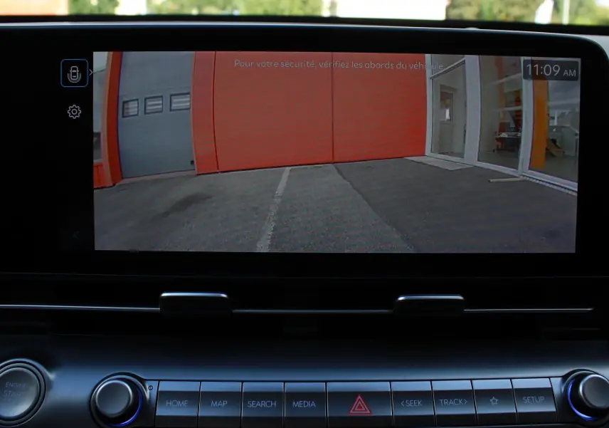 Écran central affichant la caméra de recul d’un Hyundai Kona 2024, intérieur avec commandes et bouton start/stop.