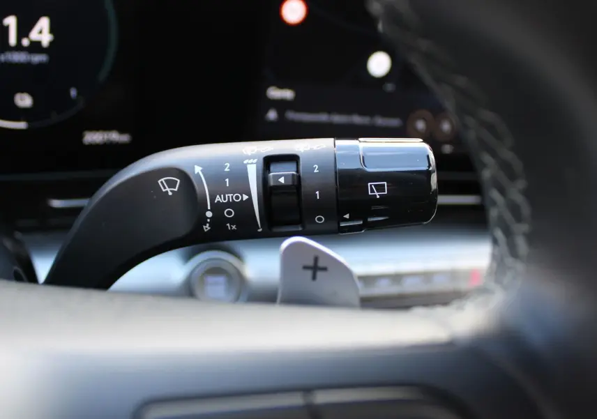 Gros plan sur la commande d’essuie-glace à gauche du volant dans l’habitacle du Hyundai Kona rouge 2024.