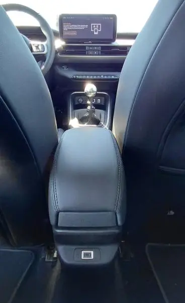 Vue intérieure arrière du Jeep Avenger 2025, montrant la console centrale noire avec levier de vitesse manuel et écran tactile.