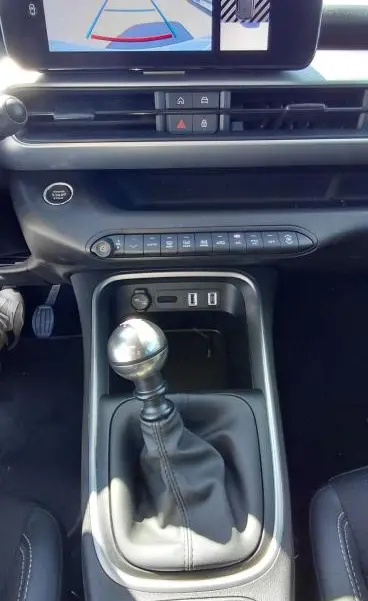 Vue intérieure centrée sur le levier de vitesse manuel et l'écran multimédia du Jeep Avenger blanc 2025, version Summit.