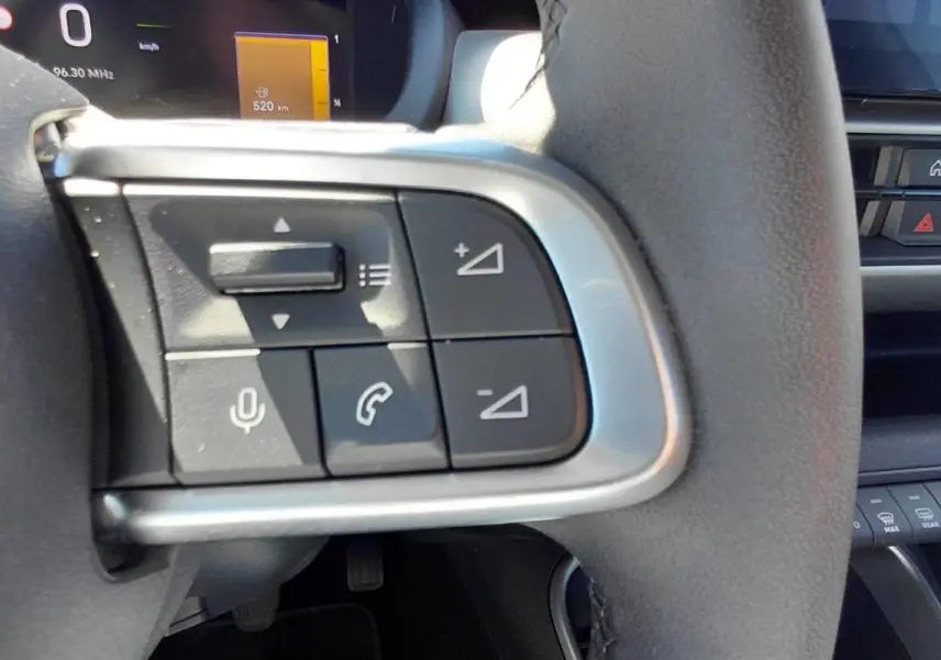 Gros plan sur les commandes au volant côté gauche du Jeep Avenger blanc 2025, avec boutons de volume et appel.