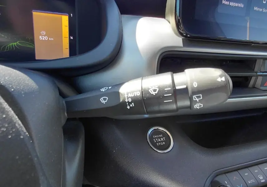 Gros plan intérieur sur la commande d'essuie-glace et le bouton start/stop du Jeep Avenger blanc, tableau de bord digital visible.