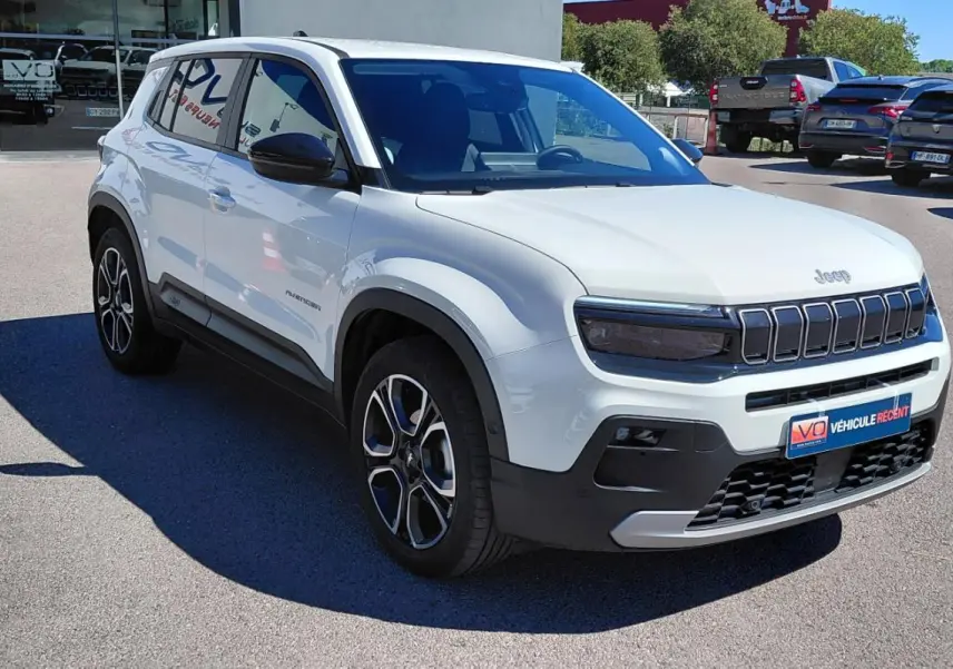 Jeep Avenger blanc en vue 3/4 avant droit, avec calandre noire distinctive et jantes alliage bicolores.