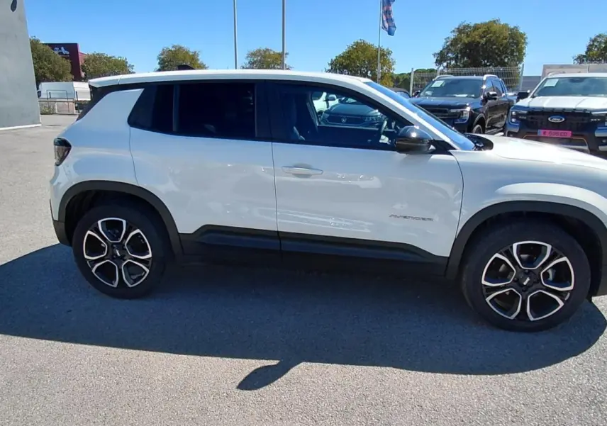 Vue de profil côté gauche d'un Jeep Avenger blanc 2025 avec jantes noires et détails noirs sur les bas de caisse.