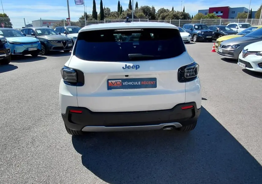 Vue arrière d'un Jeep Avenger blanc 2025 avec feux arrière noirs et pare-chocs noir contrastant sur parking.