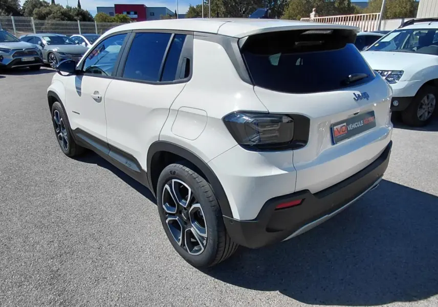 Vue 3/4 arrière droite d’un Jeep Avenger blanc 2025 avec feux arrière fumés et jantes noires distinctives.
