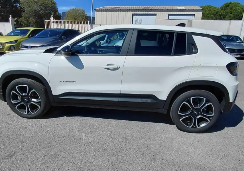 Jeep Avenger blanc vu de profil côté gauche, avec jantes noires et éléments noirs contrastants sur la carrosserie.